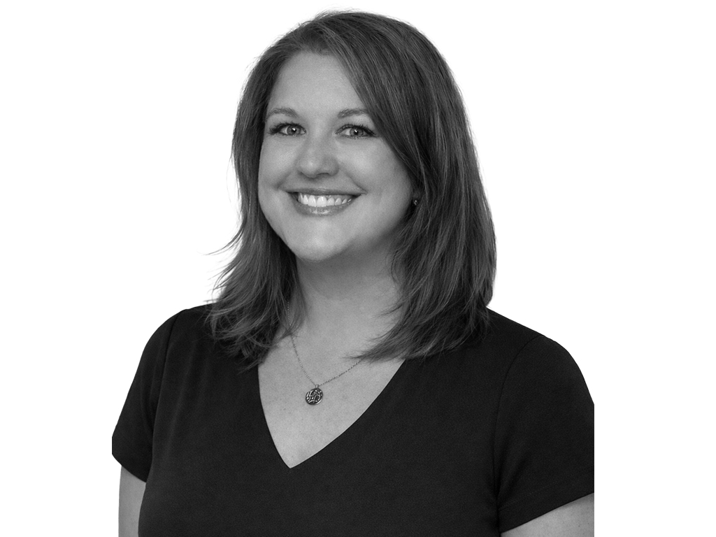 Smiling woman with shoulder-length hair in a black V-neck top, looking at the camera.